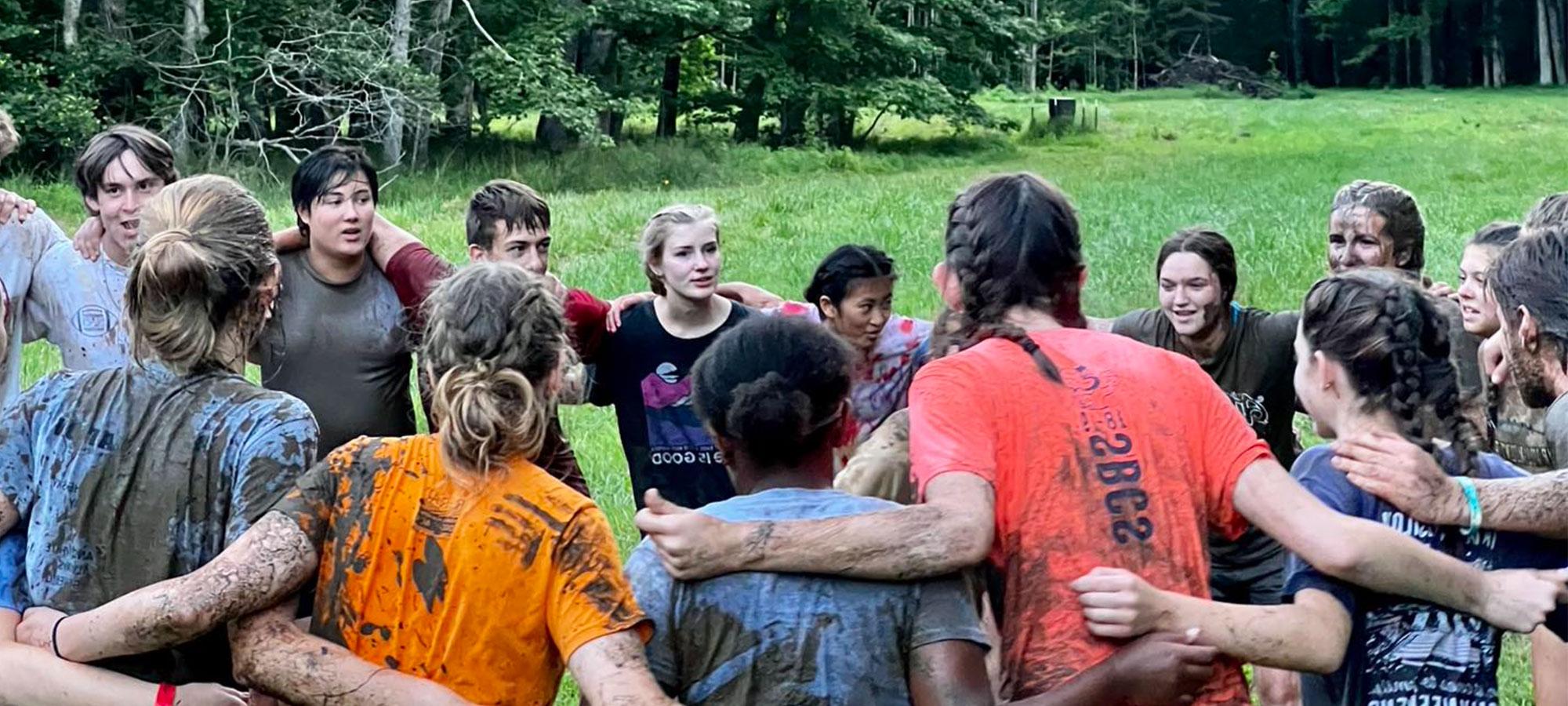 Students hugging in a circle after the mud run